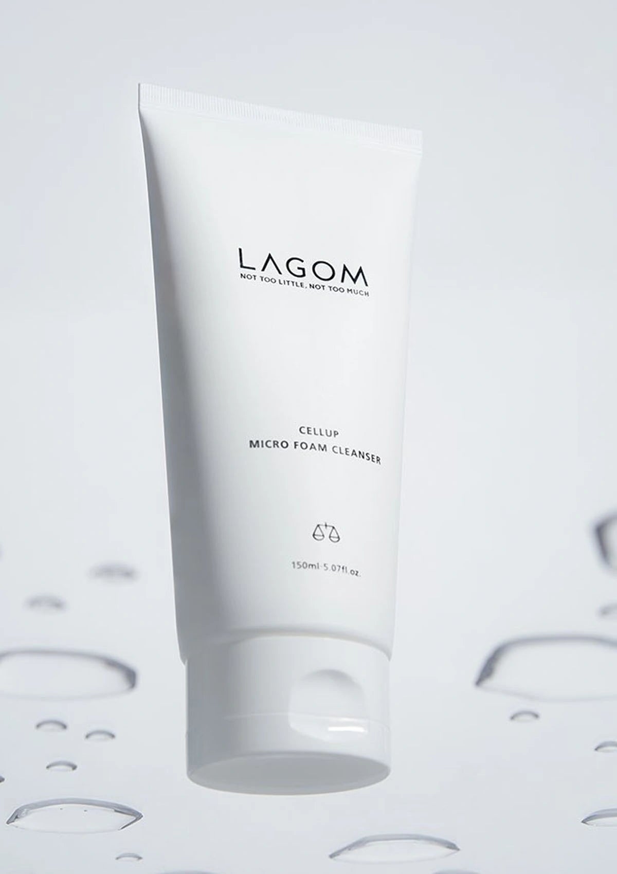 White tube of Lagom cleanser on a light gray background with water droplets.